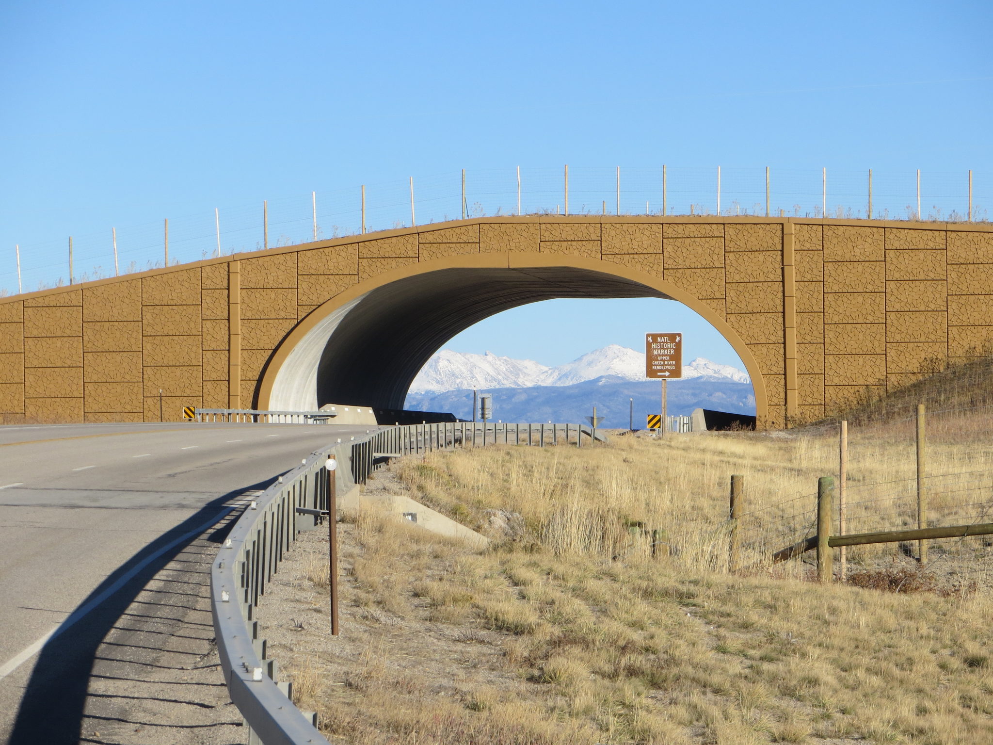Completed Reinforced Earth MSE wall supporting wildlife crossing with mountains in background seen through arch