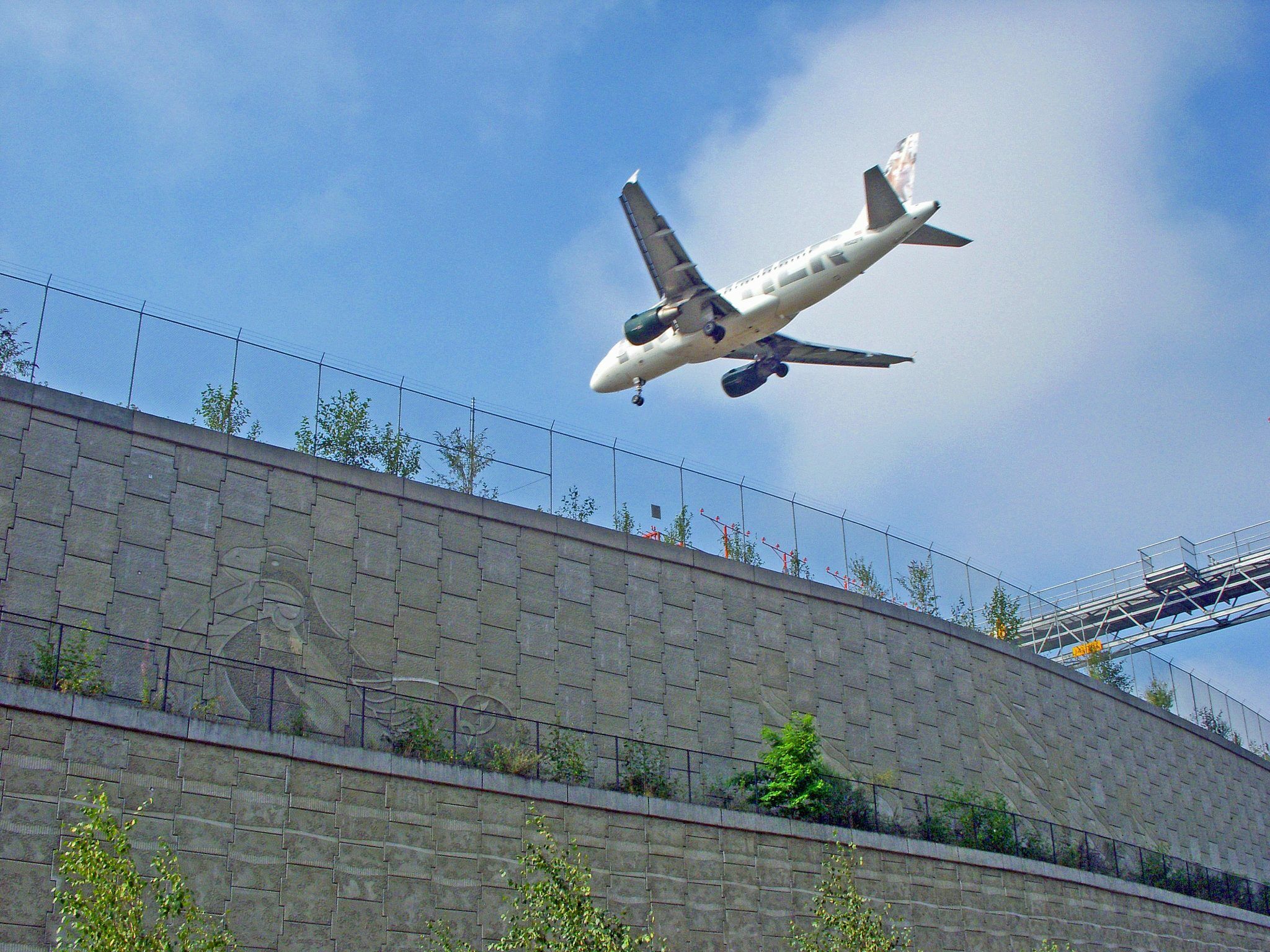 Airplane flying over large tiered Reinforced Earth MSE wall at Sea-Tac airport