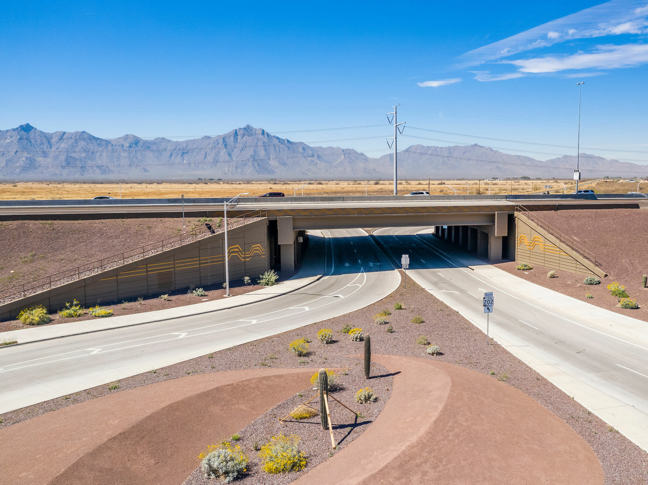 Bridge perpendicular to road, surrounded by red dirt.