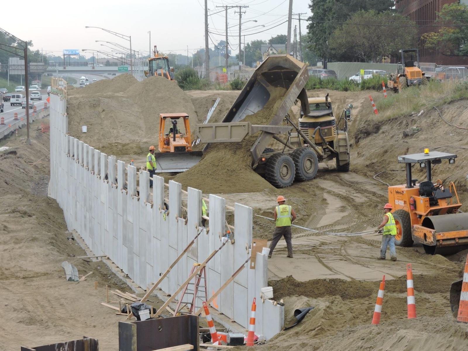 MSE wall construction with workers laying reinforcing strips